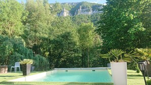 A swimming pool surrounded by lush greenery and a mountainous backdrop.