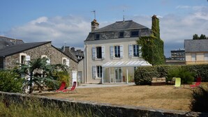Ein großes Haus mit einem geräumigen Garten, einer überdachten Terrasse und verschiedenen Sitzmöglichkeiten im Freien.