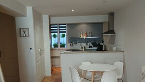 A modern kitchen with a central island, white chairs, and a dining table. - Quiet, air-conditioned apartment for 4 in city center (Cassis)