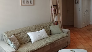 A living room with a beige sofa, a white coffee table, and a wooden ladder bookshelf. - Quiet, air-conditioned apartment for 4 in city center (Cassis)