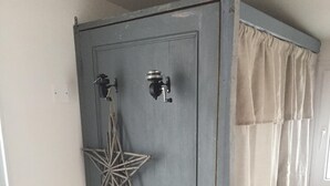 A room with a checkered floor, a white chair, a grey door with a star decoration, and a curtain. - Charming typical house  (Meschers-sur-Gironde)