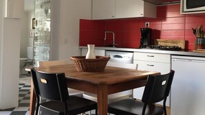 A kitchen with a checkered floor, a dining table with chairs, a microwave, and a Bosch dishwasher. - Charming typical house  (Meschers-sur-Gironde)