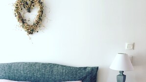 A bedroom with a bed, pillows, a heart-shaped decoration, a lamp, and a nightstand. - Charming typical house  (Meschers-sur-Gironde)