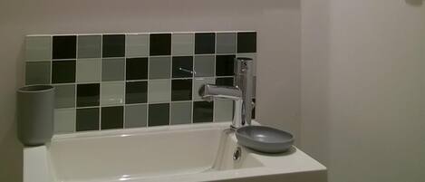 Un baño con un lavamanos blanco, un espejo y un salpicadero de azulejos.
