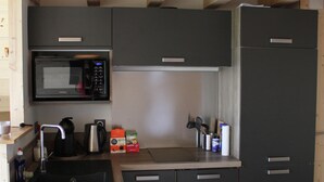 Cocina pequeña con microondas, lavaplatos y dos refrigeradores.