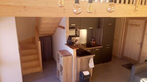 Cocina compacta con encimera de madera, cafetera y lavamanos.