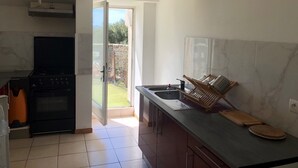 Eine Küche mit Herd, Backofen und Spüle. Ein gläserne Schiebetür führt auf einen Balkon.