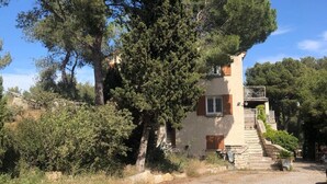 Ein Haus mit Steinstufen, die zu einer Holztür führen, umgeben von Bäumen und einer Schotterauffahrt.