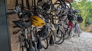 Une rangée de vélos et de casques suspendus à un mur en bois dans un garage.