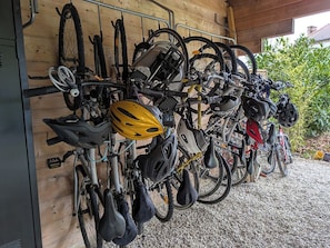 A row of bicycles and helmets hanging on a wooden wall in a garage.