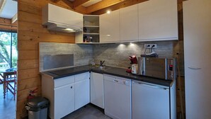 Une cuisine compacte avec des meubles blancs, un four à micro-ondes en acier inoxydable et un lave-vaisselle.