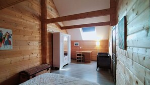 Une pièce dans un chalet en bois, comprenant un lit, un bureau et une chaise.