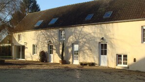 A two-story building with a sloped roof, multiple windows, and a gravel driveway. - house high capacity with private pool (Meursanges)