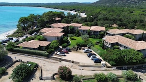 Un quartier résidentiel situé sur la côte, avec des maisons en terrasses, une plage et un parking.