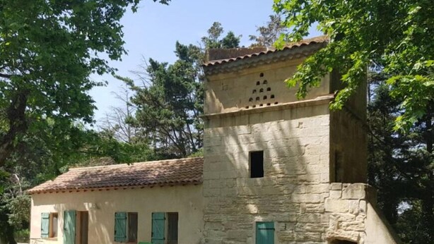 Un bâtiment en pierre avec un toit recouvert de tuiles, une petite fenêtre et une porte.