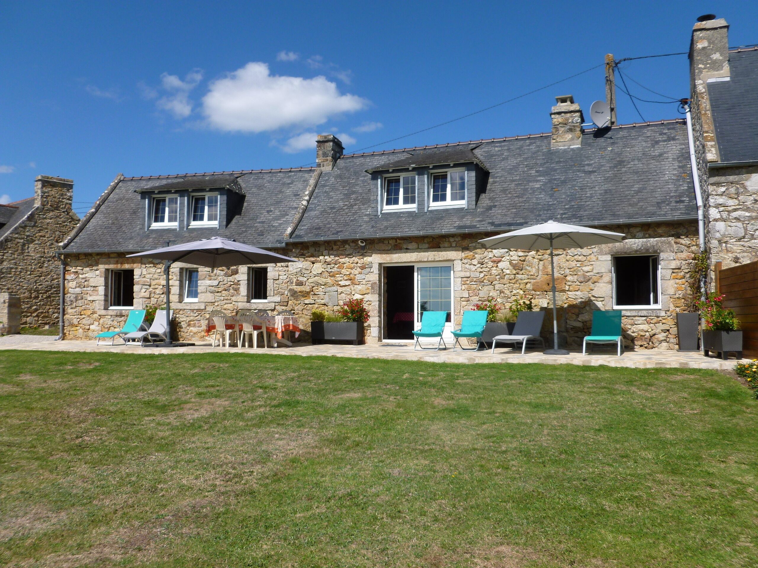 A stone house with a patio area featuring outdoor seating and a covered umbrella.