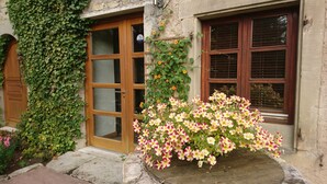 A building with a wooden door, a window with shutters, and a flower box with pink and white flowers. - GITE DE LA TOUR * * * *, SPA DETENTE MASSAGE 3 rooms with individual bathrooms (Langatte)