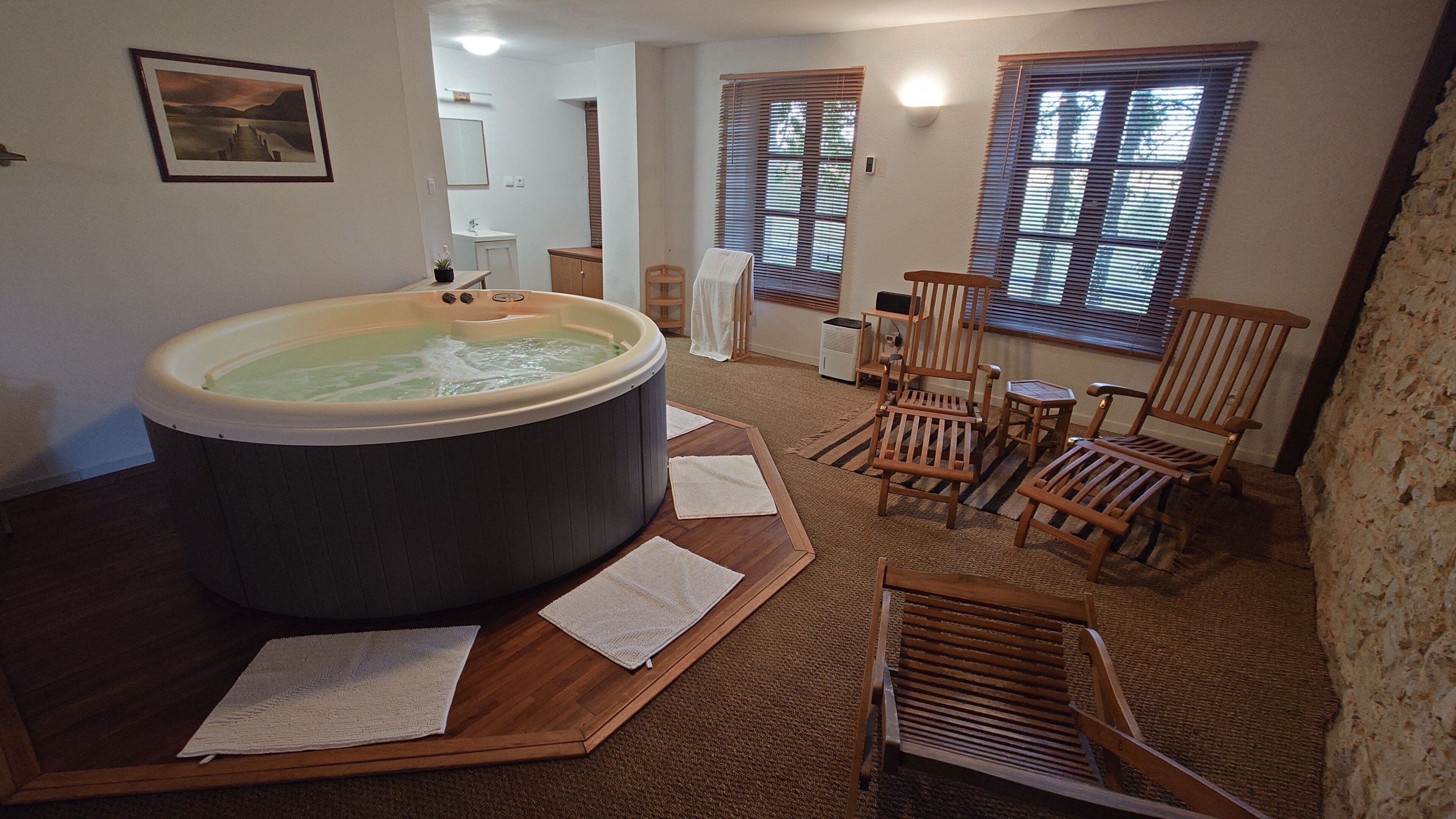 A room with a hot tub, wooden chairs, and a carpeted floor.