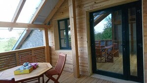 A wooden deck with a table and chairs, a sliding glass door, and a view of the outdoors. - GITE DE LA TOUR * * * *, SPA DETENTE MASSAGE 3 rooms with individual bathrooms (Langatte)