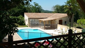 A poolside area with a clear view of a swimming pool, a covered seating area, and a building with a tiled roof. - Four independent cottages in an old farmhouse with swimming pool - "Loire" (Limbrassac)