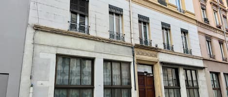 Un bâtiment doté de grandes fenêtres, d’une porte en bois et d’un vélo garé devant.