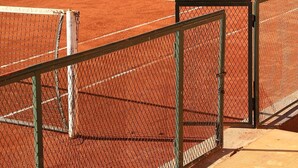 A tennis court with a chain-link fence, a net, and a wooden viewing platform. - Premium Suite for 2 in Marrakesh (Marrakech)