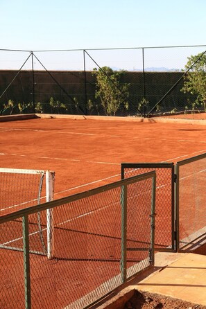 A tennis court with a chain-link fence, a net, and a wooden viewing platform. - Premium Suite for 2 in Marrakesh (Marrakech)