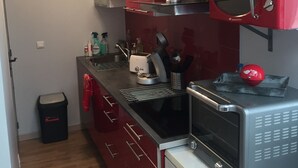 A compact kitchen with red cabinets, a microwave, a coffee maker, and a toaster.