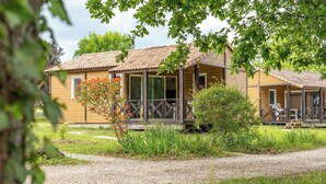 Une cabane en bois avec un toit en tuiles, une véranda et un chemin de gravier menant à l’entrée.