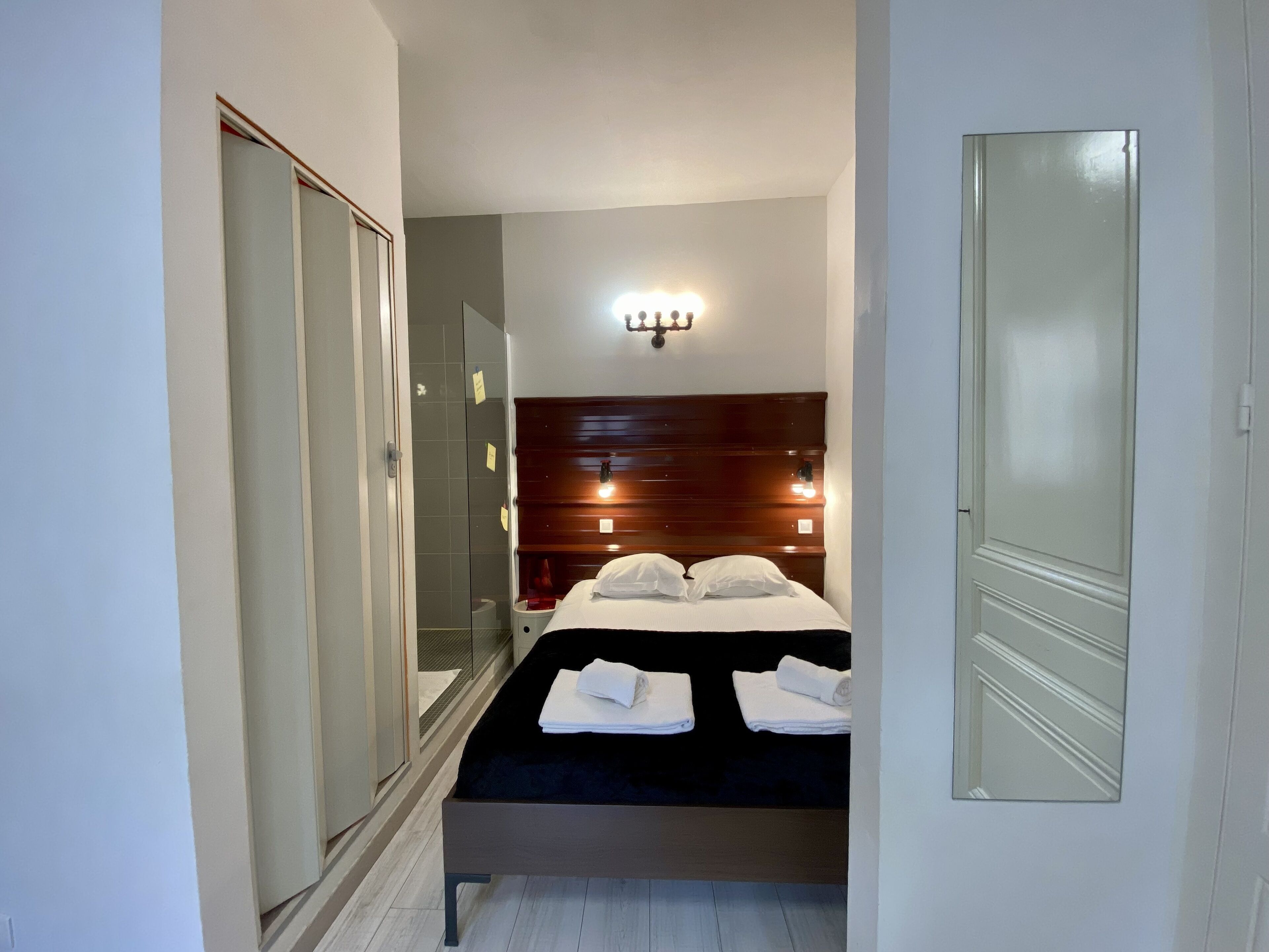 A bedroom with a bed, a wardrobe, and a mirror.