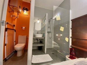Une salle de bain avec des toilettes, un lavabo et un espace douche. Il y a des notes accrochées au mur et une serviette sur le sol.