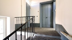 Un escalier avec une rampe noire menant à une porte.