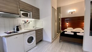 Une chambre d’hôtel compacte dotée d’une kitchenette, comprenant un four à micro-ondes, un évier et un lave-linge.