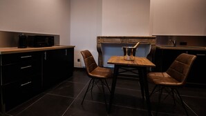 A modern kitchen with dark cabinetry, a wooden table, and two leather chairs. - Suite on 3 levels. Spa, jacuzzi, sauna and hammam. (Metz)