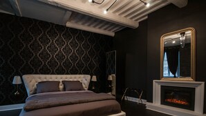 A bedroom with a tufted headboard bed, a mirror, and a fireplace. - Suite on 3 levels. Spa, jacuzzi, sauna and hammam. (Metz)