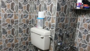 Ein Badezimmer mit Toilette, Dusche und einer Wand mit Steinmuster.