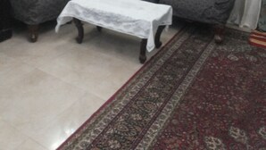 Ein Wohnzimmer mit zwei grauen Sofas, einem weißen Tisch und einem Teppich mit Muster.