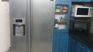 Eine Küche mit einem Edelstahl-Kühlschrank, einer Mikrowelle und blauen Schränken.