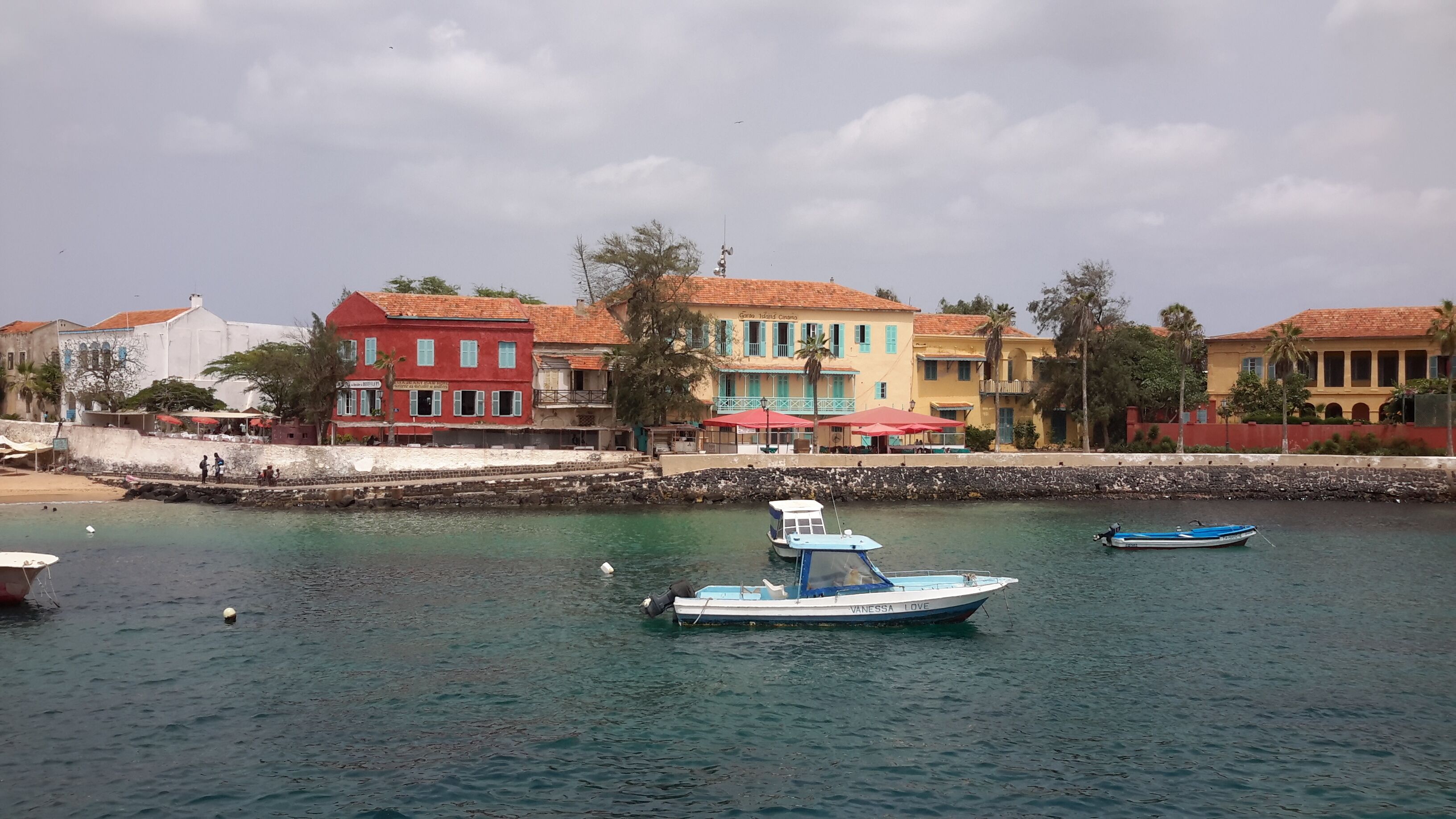 A waterfront area with colorful buildings, a sandy beach, and boats on the water.