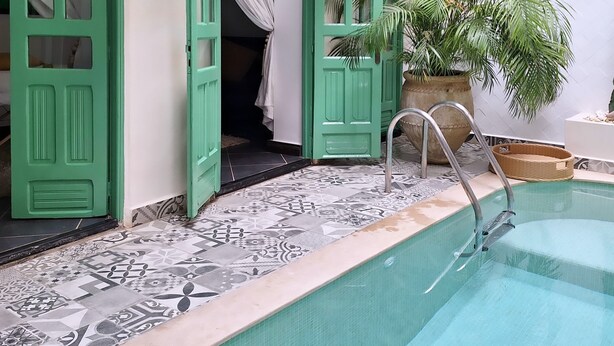 A pool area with a tiled floor, green doors, and a potted plant. - Superior room Aïlen (Médina)