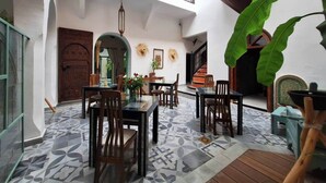 A spacious courtyard with a dining area, a wooden door, and a staircase leading to an upper level. - Superior room Aïlen (Médina)