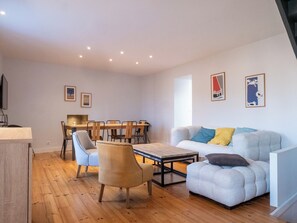 A modern living room with a sofa, armchairs, a dining table, and chairs.