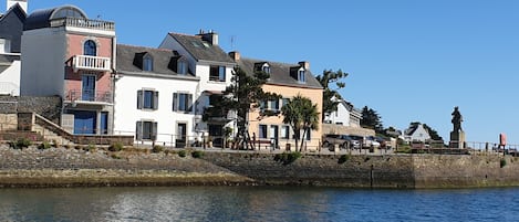A waterfront property with multiple buildings, a stone wall, and a statue.