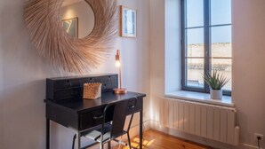 Ein modernes Zimmer mit Schreibtisch, Stühlen, einem großen Fenster, einer Heizung und einer Wanddekoration.