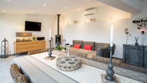 A modern living room with a sofa, a TV, a fireplace, and a dining area with a table and chairs. - House-loft 200m from downtown with garden and free parking (Beaune)