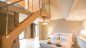 A modern hotel room with a wooden staircase, a large bed with pillows, a bedside table with a lamp, and a window with curtains. - House-loft 200m from downtown with garden and free parking (Beaune)