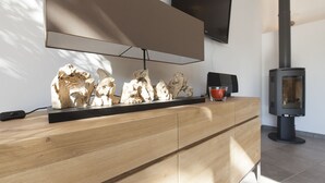 A modern kitchen with a wooden countertop, a flat-screen TV mounted above it, and a black stove on the right. - House-loft 200m from downtown with garden and free parking (Beaune)