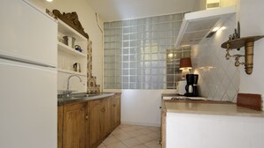 Eine kleine Küche mit Holzausstattung, integriertem Spülbecken und einem Fenster mit Gittermuster.