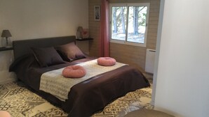 Un dormitorio con cama, almohadas, una ventana y una lámpara.