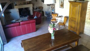 Una sala de estar con un sofá rojo, una mesa de comedor de madera y un jarrón con flores.